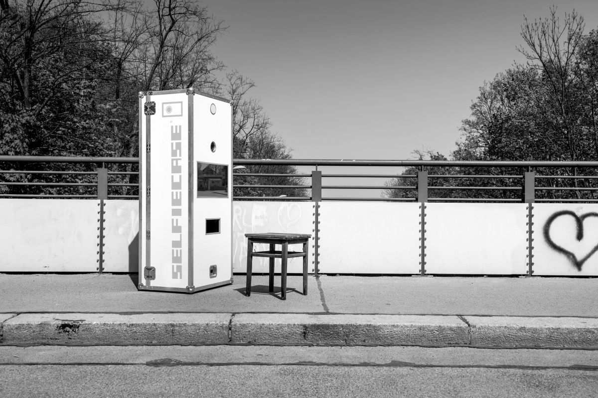 SelfieCase steht auf einer Brücke für Fussgänger. Am Brückengeländer ist ein großes Herz aufgemalt.